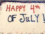 rectangular cake with white frosting and blue trim Happy fourth of July is written in red and blue icing