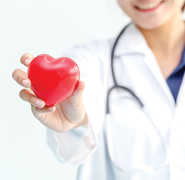 female doctor holding a red stress ball in the shape of a heart