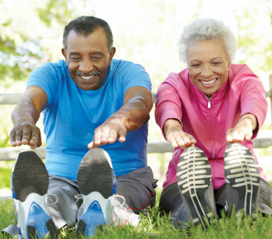 senior man and woman stretching their legs in the park