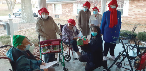 Residents from Arcadian Cove Assisted Living Facility on porch singing Christmas carols