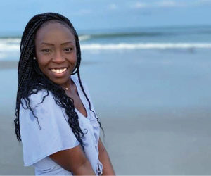 young black woman smiling for photo at the beach