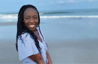 young black woman smiling for photo at the beach