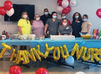 Madison nursing staff standing behind decorated table with sign saying Thank You Nurses