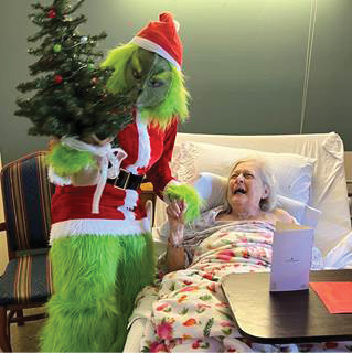 Madison Health and Rehab resident pictured with The Grinch stealing her Christmas Tree